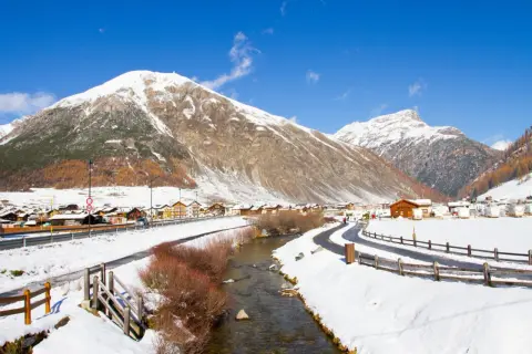 Livigno a novembre: un paesaggio innevato con montagne maestose, un fiume serpeggiante e un villaggio alpino. Ideale per scoprire cosa fare a Livigno in questo periodo.