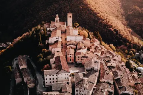 Borghi vicino Nocera Umbra, un gioiello medievale arroccato su una collina, con torri e tetti in terracotta immersi nel verde autunnale.