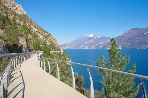 Una moderna ciclabile a picco sul lago, con montagne sullo sfondo. Potrebbe essere la ciclabile più bella d'Italia.