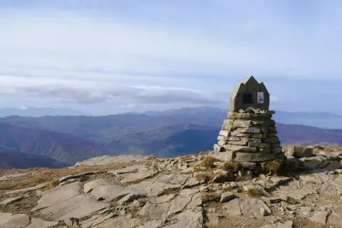 Cairn in pietra sulla cima del monte più alto Emilia Romagna, con vista panoramica sulle colline sottostanti.