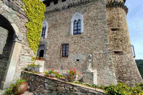 Antica dimora a Compiano, Parma, con mura in pietra, edera rampicante, fiori e una statua.