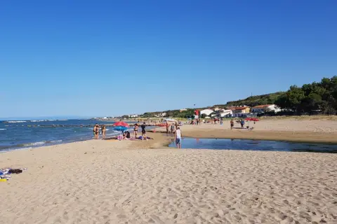 Gente rilassata sulle bellissime spiagge di Termoli, con il mare azzurro e la costa verdeggiante sullo sfondo.