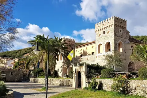 Antico palazzo con torri merlate, palme e un giallo vessillo, incantevole scenario per le terme naturali Cilento.