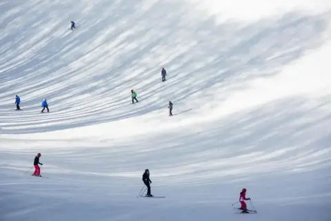 Sciare nel Lazio: persone godono della neve su una pista, con ombre suggestive degli alberi.