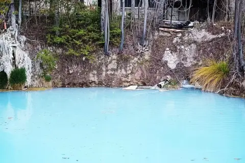 Acque azzurre e torbide delle terme di Cotilia, con vegetazione rigogliosa e rocce erose.