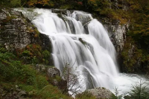 Cascata di Sant'Anna al Pelago, un velo d'acqua bianca scende tra rocce e vegetazione autunnale.