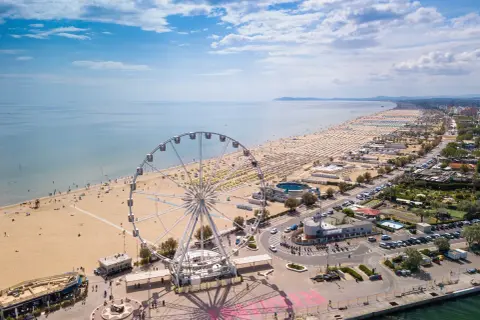 Ruota panoramica su una delle spiagge più belle dell'Emilia Romagna, con ombrelloni dorati e mare azzurro.
