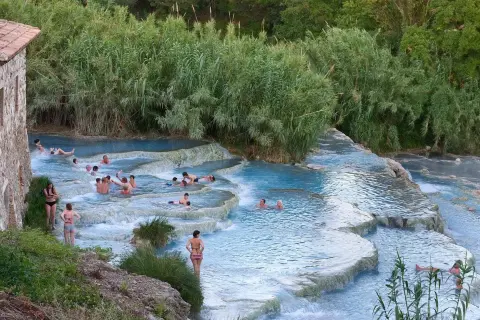 Persone si rilassano nelle cascate termali naturali. Un luogo ideale per scoprire le terme Pavia prezzi.