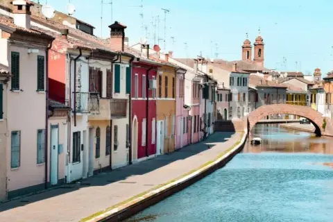 Comacchio: case colorate lungo il canale, un ponte ad arco e torri. Ideale per scoprire cosa vedere a Comacchio e dintorni in due giorni.
