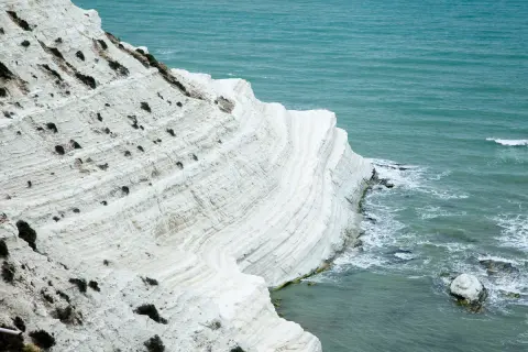 La scogliera bianca di Sicilia, con le sue stratificazioni calcaree, si tuffa nel mare turchese.