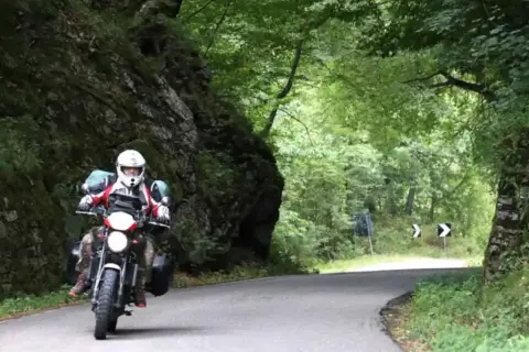 Motociclista in un percorso tortuoso tra rocce e alberi. Un'avventura di giri in moto in Emilia Romagna.