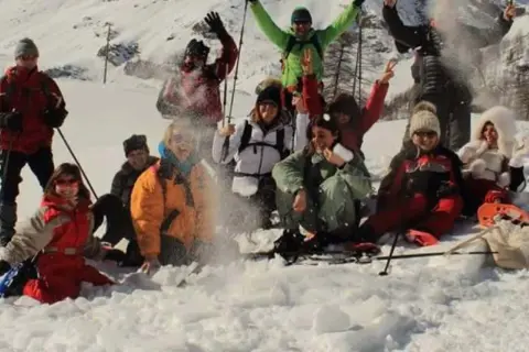 Un gruppo di amici si diverte con le ciaspolate in Val d'Aosta, tra risate e lanci di neve.