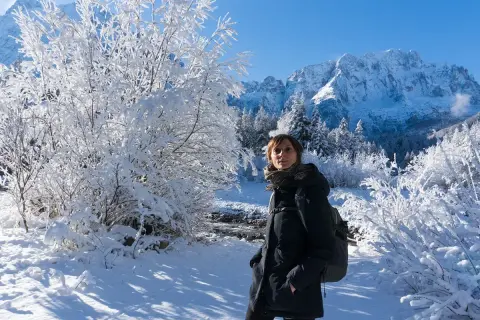 Donna con zaino in un paesaggio invernale innevato, montagne sullo sfondo. Val Saisera incanta con la sua bellezza.