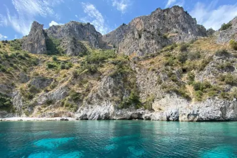 Paesaggi mozzafiato mare: scogliere rocciose ricoperte di vegetazione si tuffano in acque cristalline e turchesi.