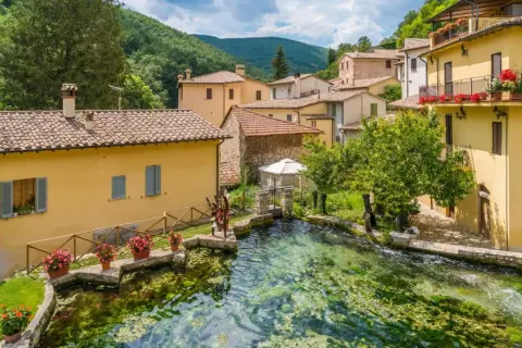 Borgo pittoresco con case gialle e un ruscello cristallino. Un'ottima meta per scoprire cosa vedere vicino Assisi.