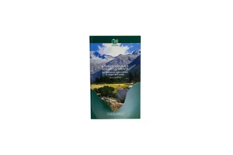 Copertina del libro "Il Parco Naturale Adamello Brenta", con montagne innevate, un fiume e un ponte.
