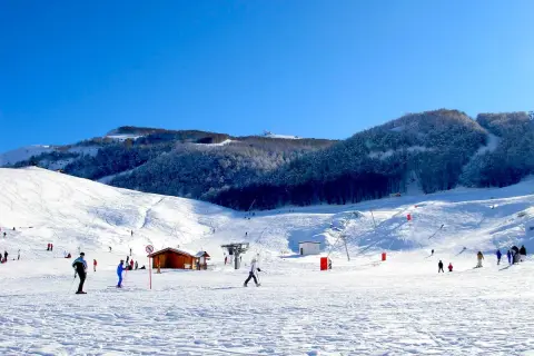 Piste innevate e sciatori in azione, un perfetto esempio di dove si scia in Abruzzo. Montagne innevate e cielo azzurro.