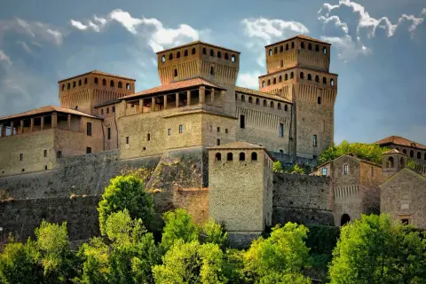 Roccastraordinaria di Torrechiara, un gioiello incastonato tra le colline di Parma, Emilia Romagna, con torri imponenti e un cielo drammatico.