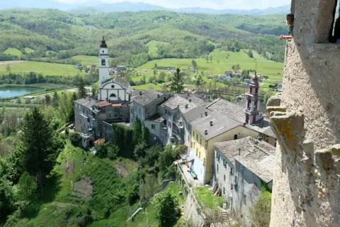 Un borgo incantevole con un campanile bianco, tetti in pietra e colline verdi. Un luogo dove compiano cosa vedere, tra storia e natura.