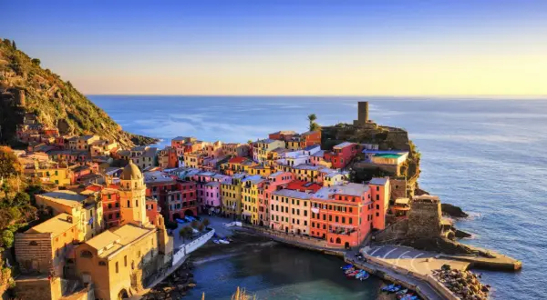 Coloratissimi borghi sul mare aggrappati alla scogliera, con il sole che illumina le case e il blu intenso del mare.