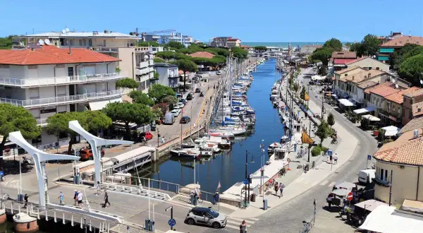 Un canale navigabile a Cervia, dove si trova un vivace porto turistico con barche a vela ormeggiate e case colorate lungo le rive.
