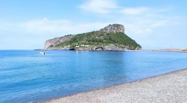 Acque azzurre e una spiaggia di ciottoli nel **golfo di Policastro**, con un'isola verdeggiante sullo sfondo.