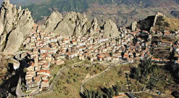 Un pittoresco borgo in Basilicata, aggrappato a rocce imponenti, con case dai tetti rossi che si estendono sul pendio.