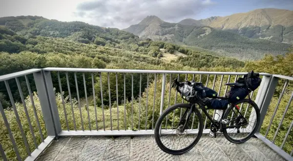 Bicicletta da cicloturismo pronta per esplorare l'Appennino Tosco Emiliano, con un panorama mozzafiato di boschi e montagne.
