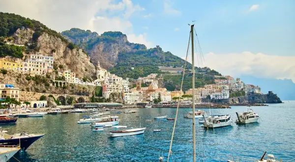 Un incantevole mare a Napoli, con un borgo colorato aggrappato alla scogliera e barche che ondeggiano nell'acqua cristallina.
