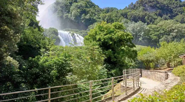 Sentiero panoramico nella Valnerina con la cascata che si intravede tra il verde lussureggiante.
