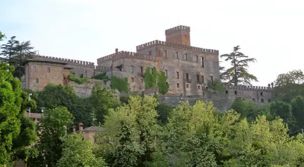 Castello medievale su una collina, circondato da alberi verdi. Un esempio dei suggestivi borghi vicino Parma.
