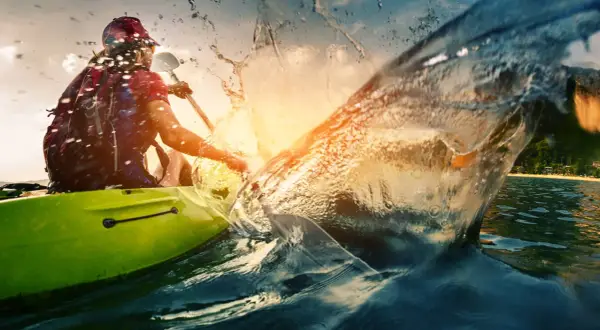 Persona in kayak crea un'onda spettacolare, un'immagine perfetta per le vacanze sportive.