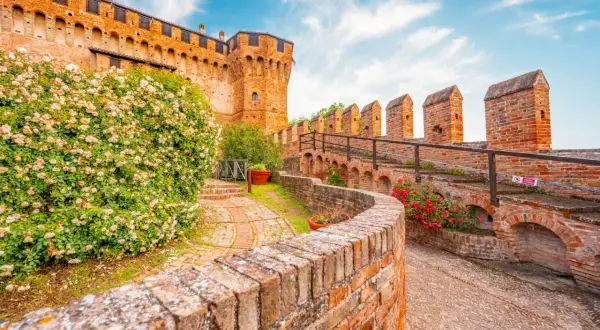 Un sentiero tra rose e mattoni rossi porta verso un castello, un assaggio dei 5 borghi più belli delle Marche.