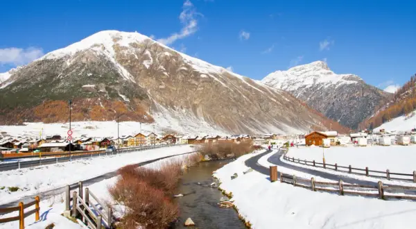 Livigno a novembre: un paesaggio innevato con montagne maestose, un fiume serpeggiante e un villaggio alpino. Ideale per scoprire cosa fare a Livigno in questo periodo.