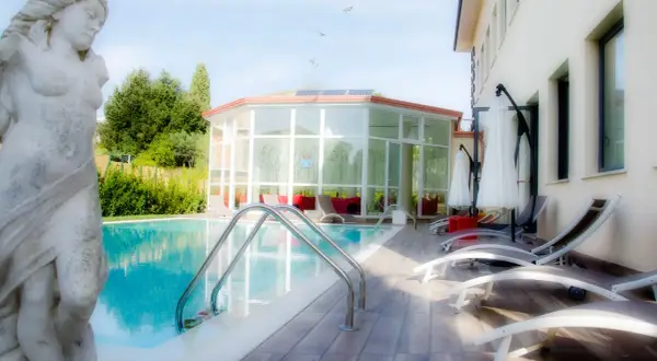 Statua classica vicino alla piscina, con un edificio moderno e un giardino lussureggiante. Un'oasi di relax a Gambassi Terme.