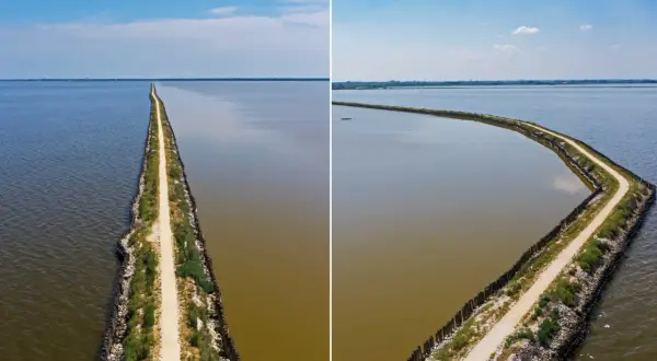 La ciclabile degli angeli, un sentiero che divide acque limpide e torbide, si estende all'infinito sotto un cielo azzurro.