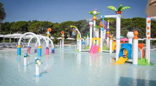 Area giochi acquatica colorata con scivoli e spruzzi d'acqua, perfetta per divertirsi alle terme Lignano.