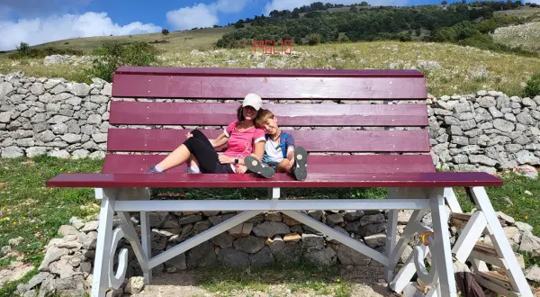 Una donna e un bambino si godono una pausa su una panchina in una montagna vicino Roma.