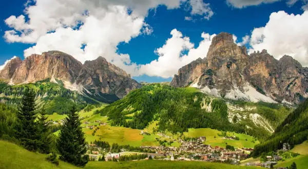 Un villaggio alpino incastonato tra imponenti vette rocciose e verdi pascoli. Una splendida località di montagna.
