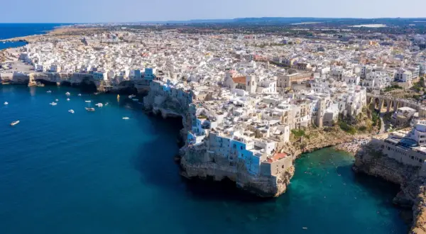 Vista aerea di Polignano a Mare, con le case bianche a picco sul mare blu intenso. Un gioiello della Valle d'Itria, dove il mare incontra la terra.