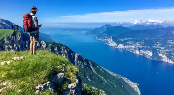 Escursionista ammira il panorama mozzafiato dal Monte Baldo. Cosa vedere: il lago blu intenso e le montagne verdi.