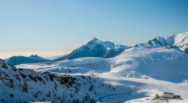 Un paesaggio innevato con piste da sci e una baita, una montagna vicino Milano a 1 ora di distanza.