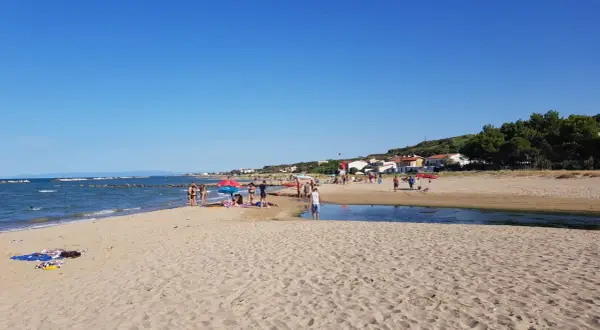 Gente rilassata sulle bellissime spiagge di Termoli, con il mare azzurro e la costa verdeggiante sullo sfondo.