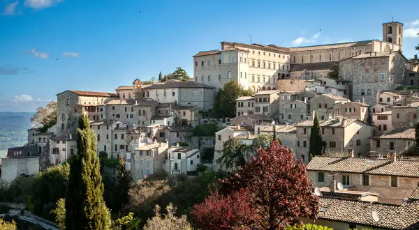 Un borgo medievale arroccato su una collina, con case in pietra e un imponente palazzo. Questo è dove si trova Todi, un gioiello umbro.