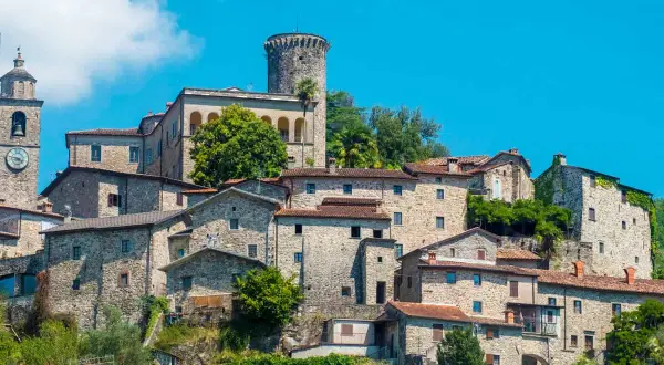 Antico borgo arroccato tra le colline dell'Appennino Tosco Emiliano, con case in pietra e una torre medievale.