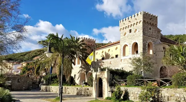 Antico palazzo con torri merlate, palme e un giallo vessillo, incantevole scenario per le terme naturali Cilento.