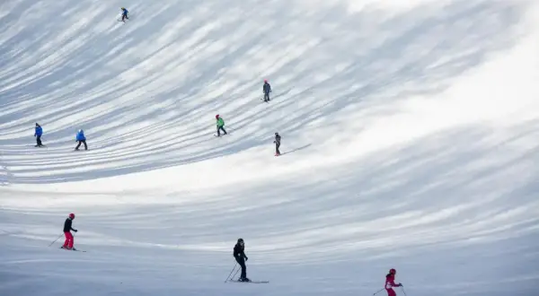 Sciare nel Lazio: persone godono della neve su una pista, con ombre suggestive degli alberi.