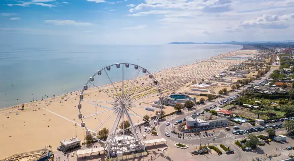 Ruota panoramica su una delle spiagge più belle dell'Emilia Romagna, con ombrelloni dorati e mare azzurro.