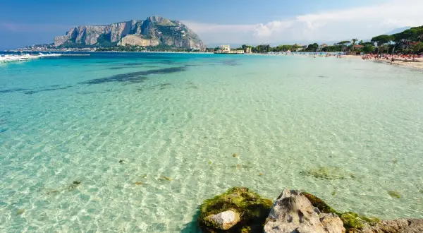 Splendido mare cristallino vicino Palermo, con la costa e il Monte Pellegrino sullo sfondo.