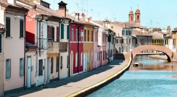 Comacchio: case colorate lungo il canale, un ponte ad arco e torri. Ideale per scoprire cosa vedere a Comacchio e dintorni in due giorni.